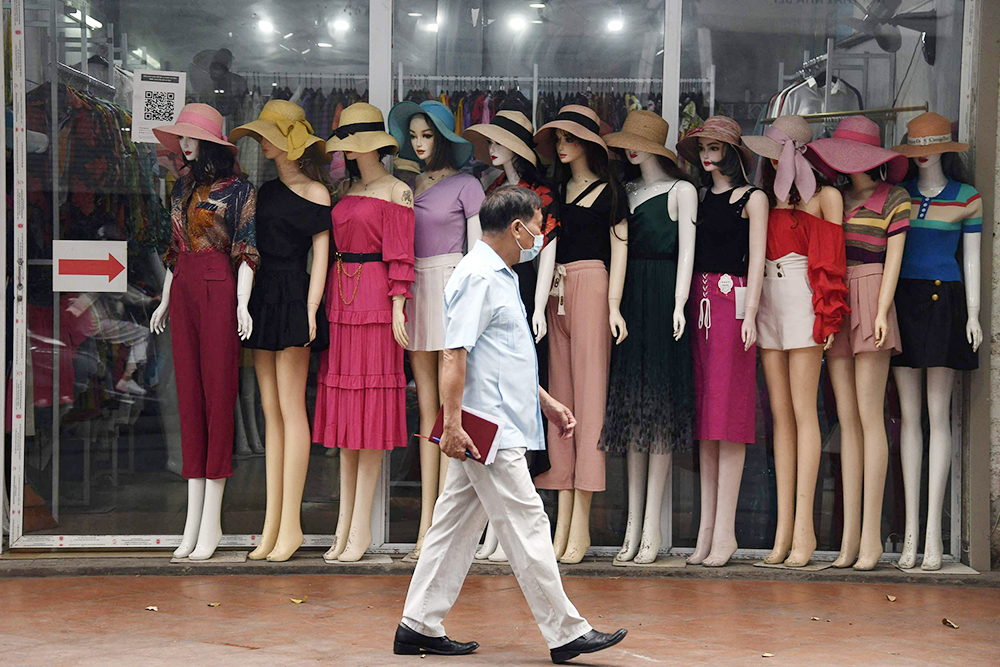 2022年6月29日,越南河内,一名男子从一家服装店外的人体模型旁走过.