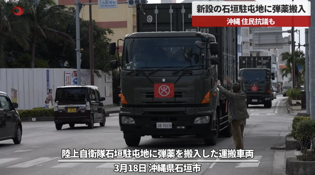 18日，当地民众在运输车前挥手试图阻拦。图自共同社