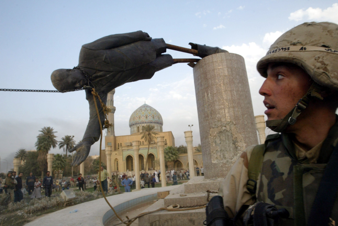 这是2003年4月9日，在巴格达市中心，一名美军士兵站在被拉倒的萨达姆塑像前。新华社发
