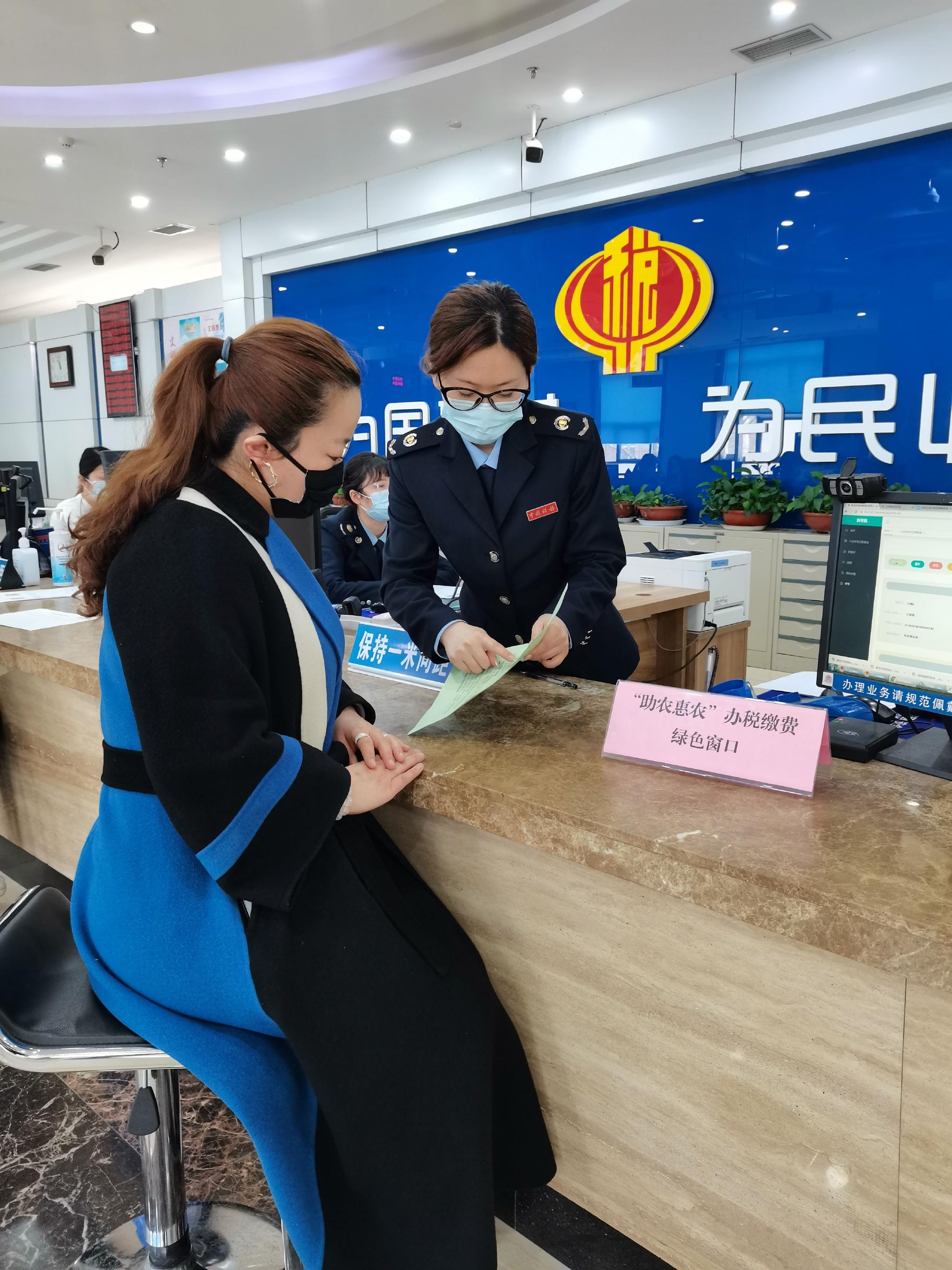 在青岛莱西市"助农惠农"办税缴费绿色窗口,工作人员为办事群众讲解