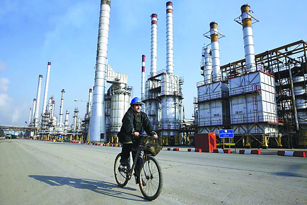 沙伊两国或开展能源产业协作。图为伊朗石油工人骑车穿行德黑兰附近的炼油工厂。（法新社）