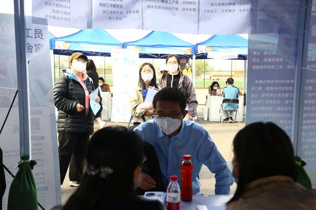 3月31日，北京朝阳体育中心，“展翼未来 才子朝阳”招聘会上，求职者驻足观看招聘单位待遇介绍。王弘晢/摄