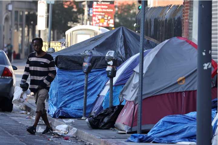 2022年8月8日,一位无家可归的男子走过美国加州洛杉矶市区的人行道,他