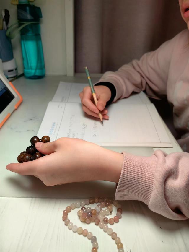 上海四年级小学生意意一边盘串一边写作业.家长供图