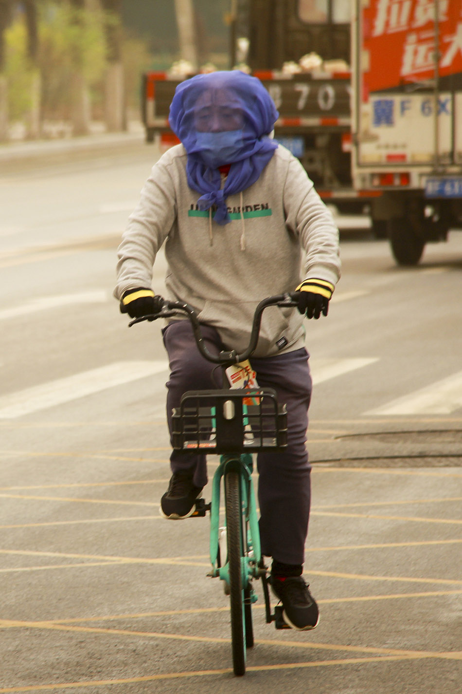 2023年4月11日,沈阳,大风沙尘天气中,市民蒙着纱巾,骑车出行.
