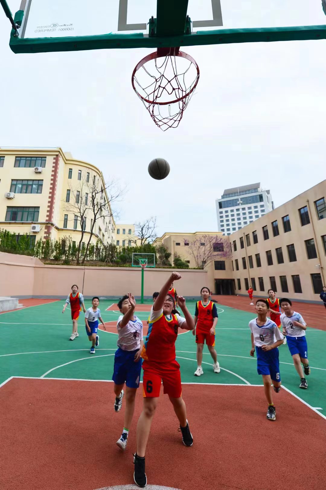 4月14日,在青岛市市北区上海路小学篮球场内,学生在争抢投篮.