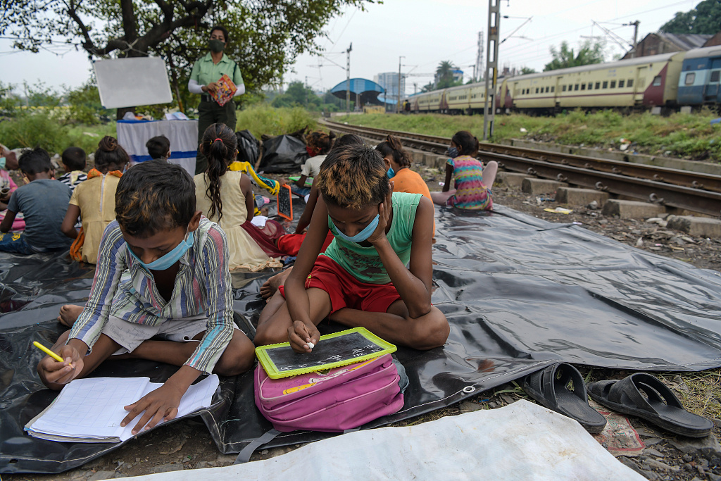 当地时间2021年8月13日,印度加尔各答,孩子们在贫民窟的铁轨旁,正在上