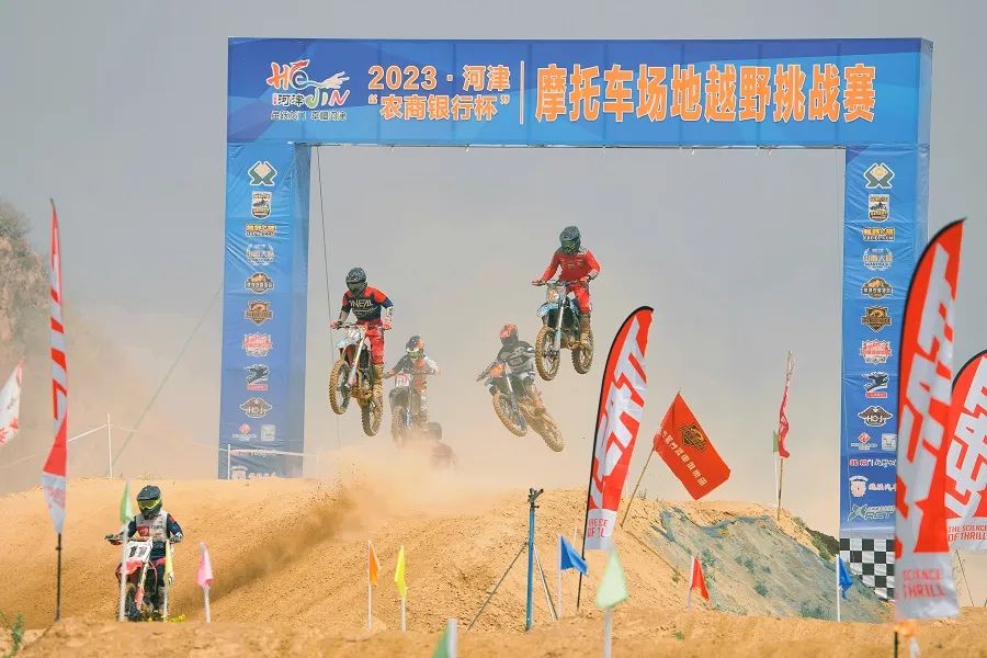 图为在河津市举办的摩托车场地越野挑战赛上,车手们在赛道上腾空跃起