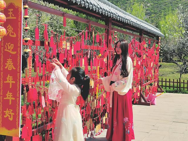 图为游客身着汉服悬挂祈福牌.