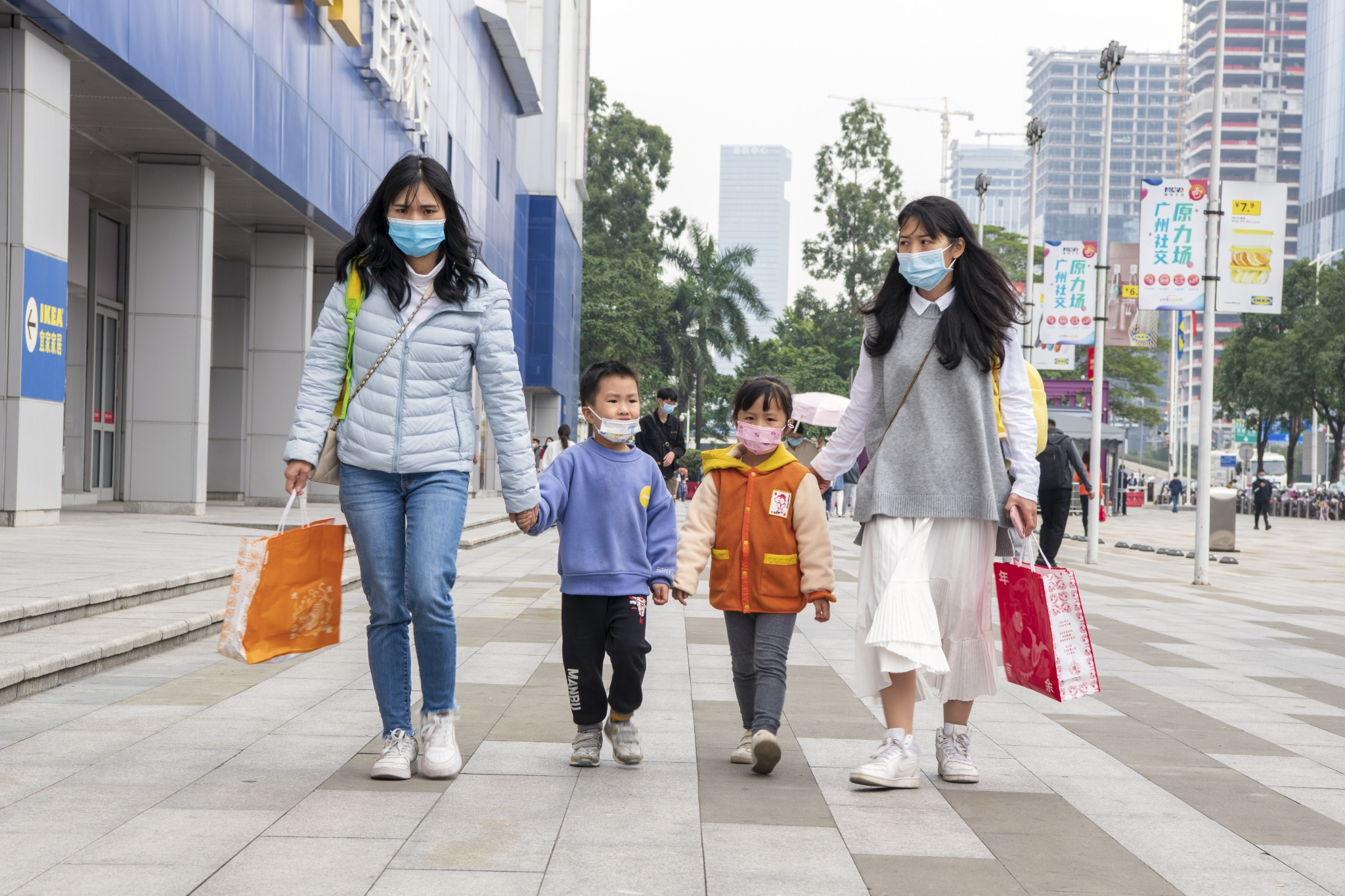 ▲广州街头，家长带着孩子经过商场。图/IC photo