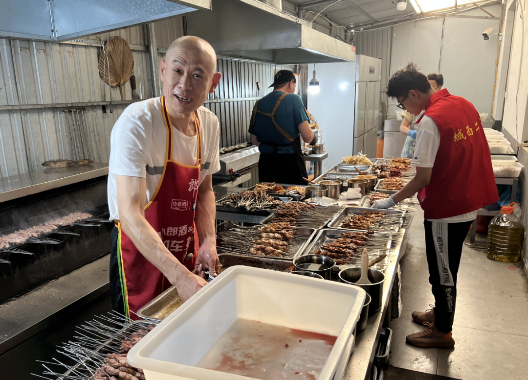 (烤串师傅徐春正在后厨制备烤串)
