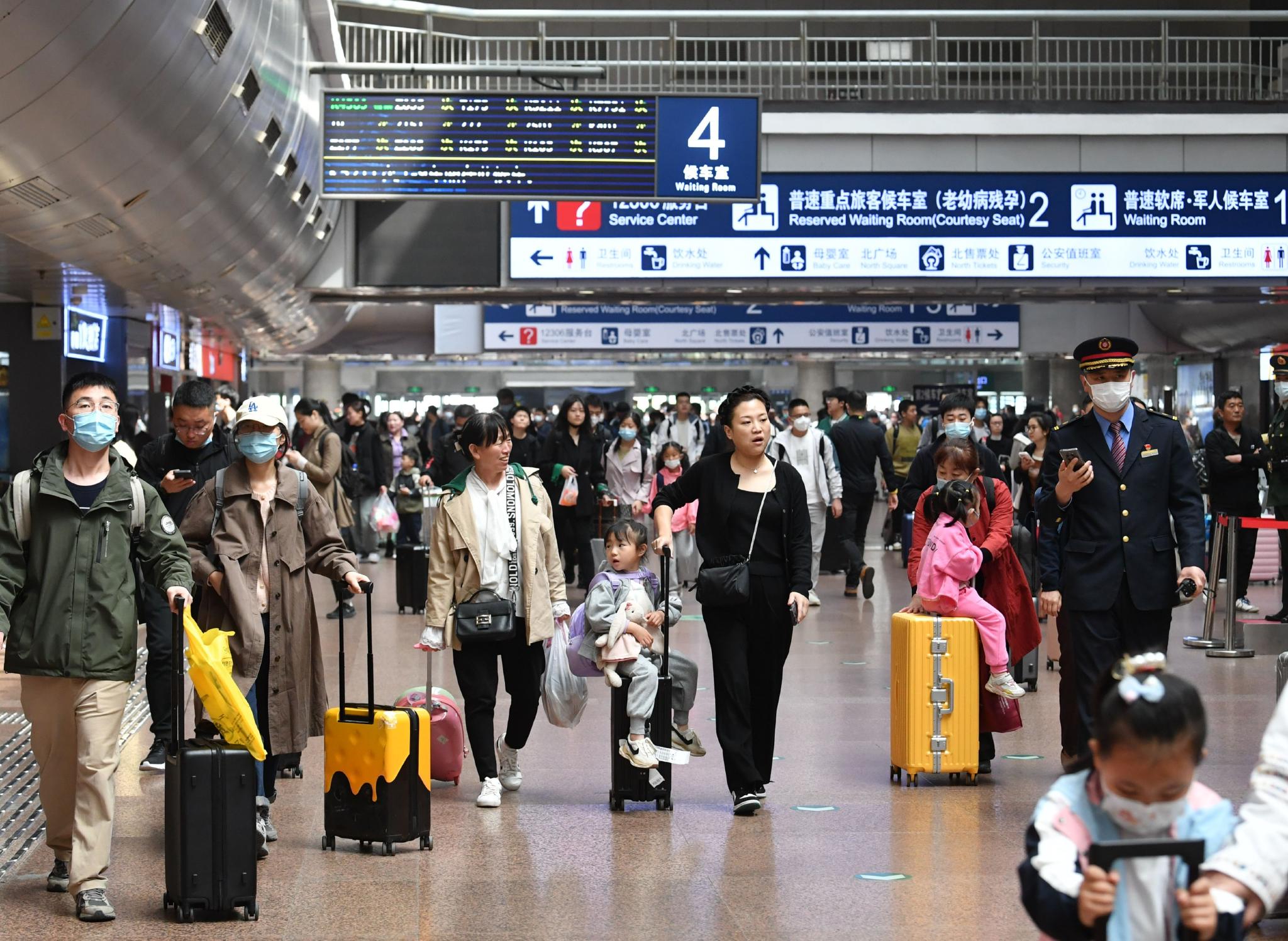 4月28日中午,北京西站迎来客流高峰,大量旅客拖着行李走在站厅内.