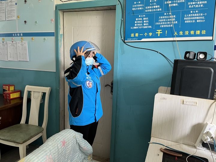 2023年4月24日,在宁夏银川,外卖女骑手丁国梅在站点内整理着装,为即将到来的送餐高峰做准备。新华社记者 任玮 摄