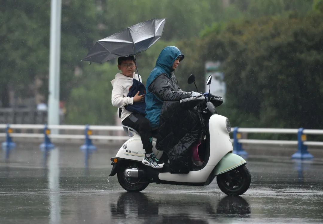5月3日,安徽阜阳,市民在雨中骑行,伞被大风吹翻.图/视觉中国
