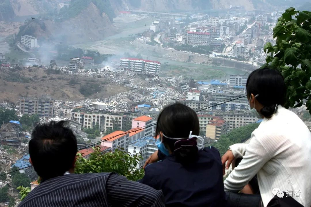 2008年5月22日,几位群众在被地震摧毁的北川县城边的山坡上,遥望