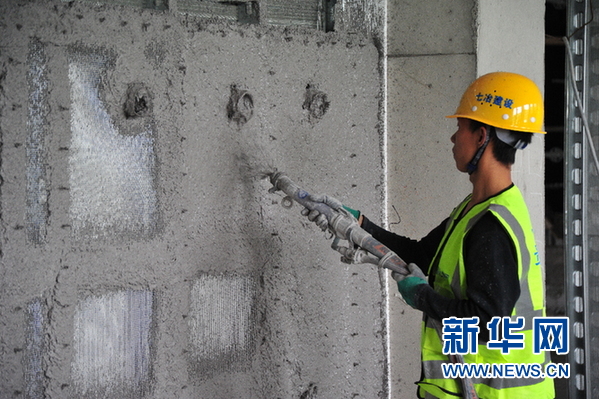 贵州理工学院三期项目工地,工人用喷枪进行磷石膏喷筑墙体施工