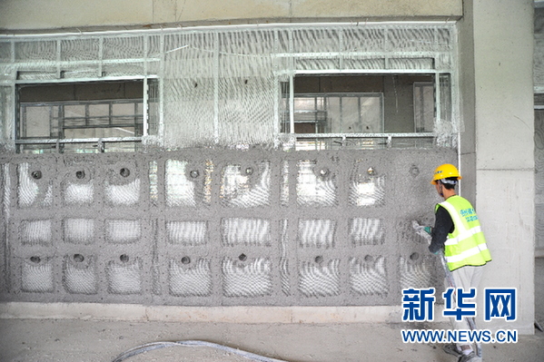 4月27日,贵州理工学院三期项目工地,一名工人进行磷石膏喷筑墙体施工.