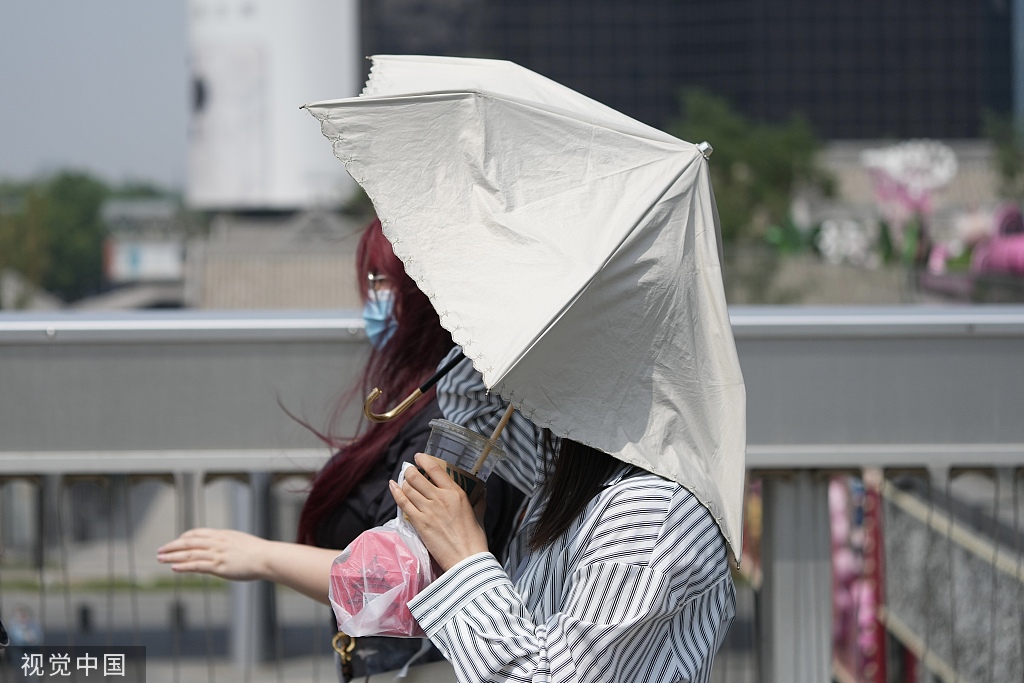 2023年5月15日,北京艳阳高照,高温蓝色预警持续,市民撑伞遮阳.