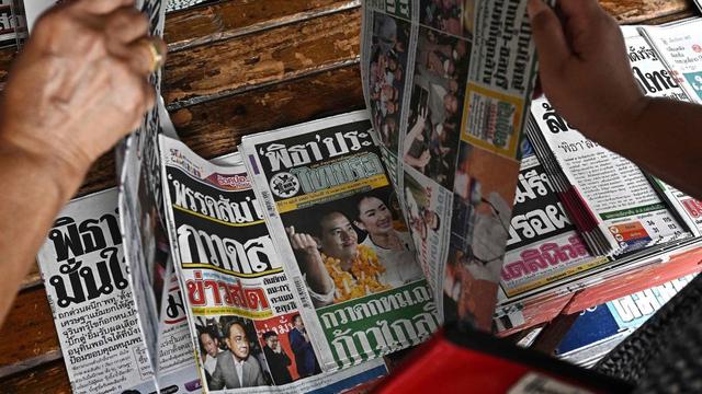 泰国曼谷,在一个报摊上,人们浏览着报纸头版,上面有他们对泰国大选的