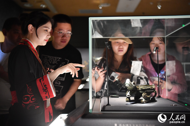 讲解员正在为游客讲解新展出的鎏金镶玉龙首四足青铜匜.