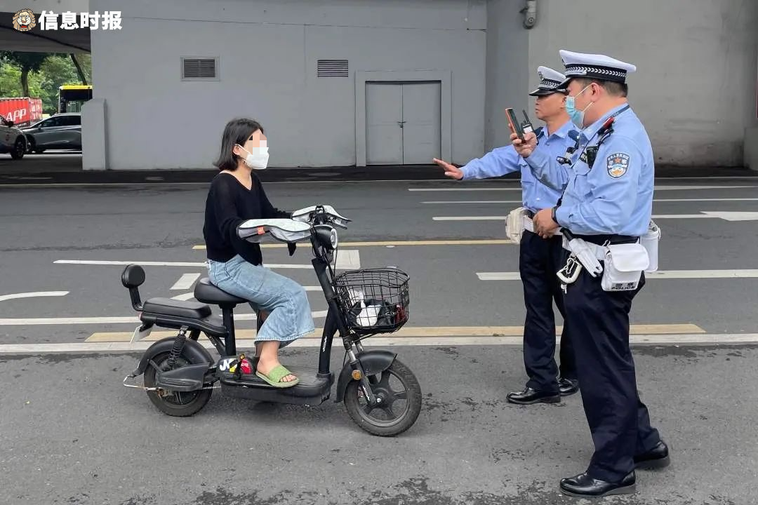 一名骑电动自行车的女子因未戴头盔,被交警拦下.