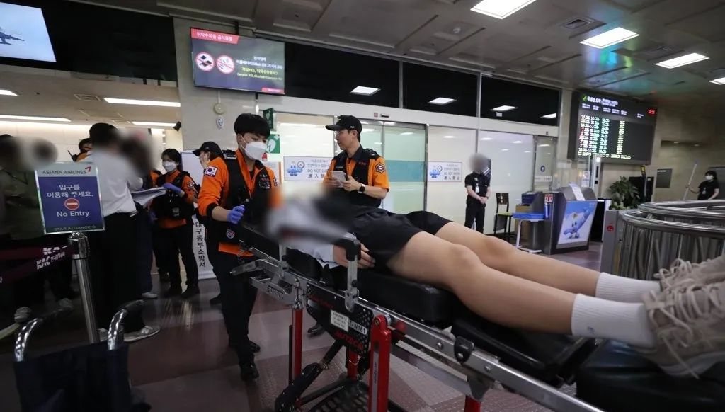 飞机在大邱国际机场紧急降落后，有身体不适者被担架抬走。图源：韩媒