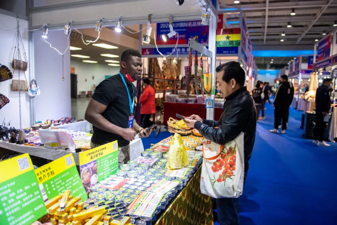 ▲资料图片：3月29日，在湖南国际会展中心，参展商（左）向观众介绍加纳商品。（新华社发）