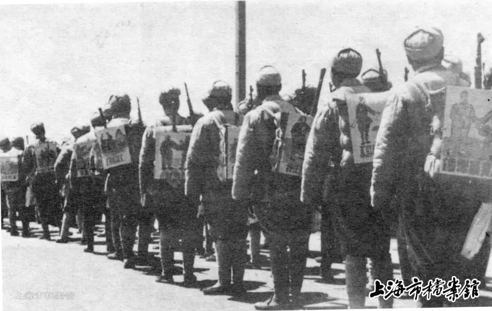 解放军战士们将《入城守则和纪律》绘成图片，挂在背包上，一边行军一边学习