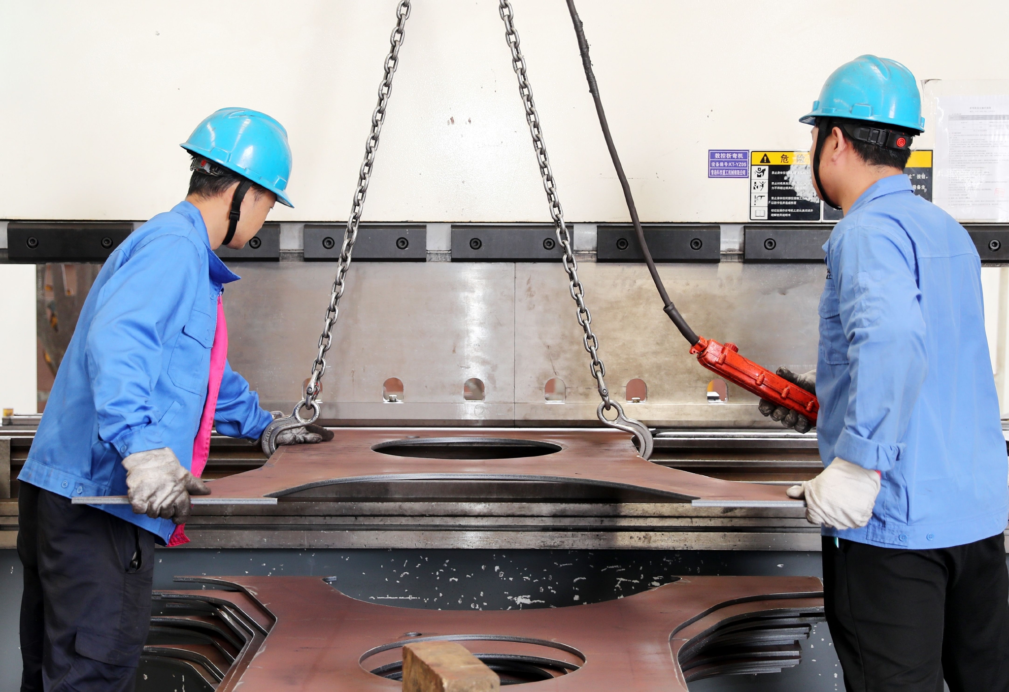 在青岛科泰重工机械有限公司,工人在对机械零配件进行后期加工