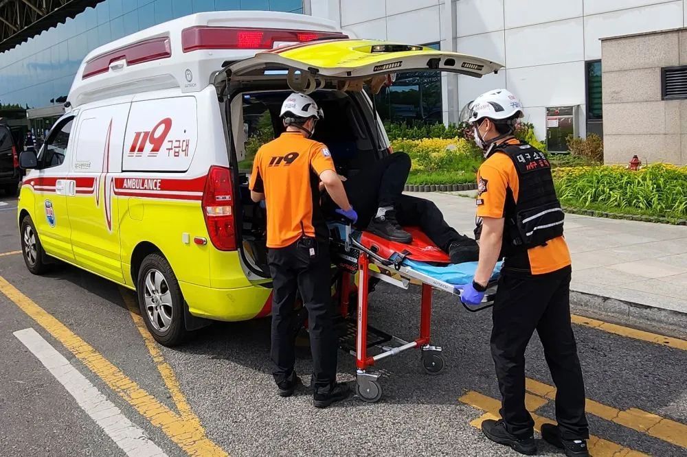 在韩国大邱机场,救援人员用担架将出现呼吸困难的乘客转移到救护车上