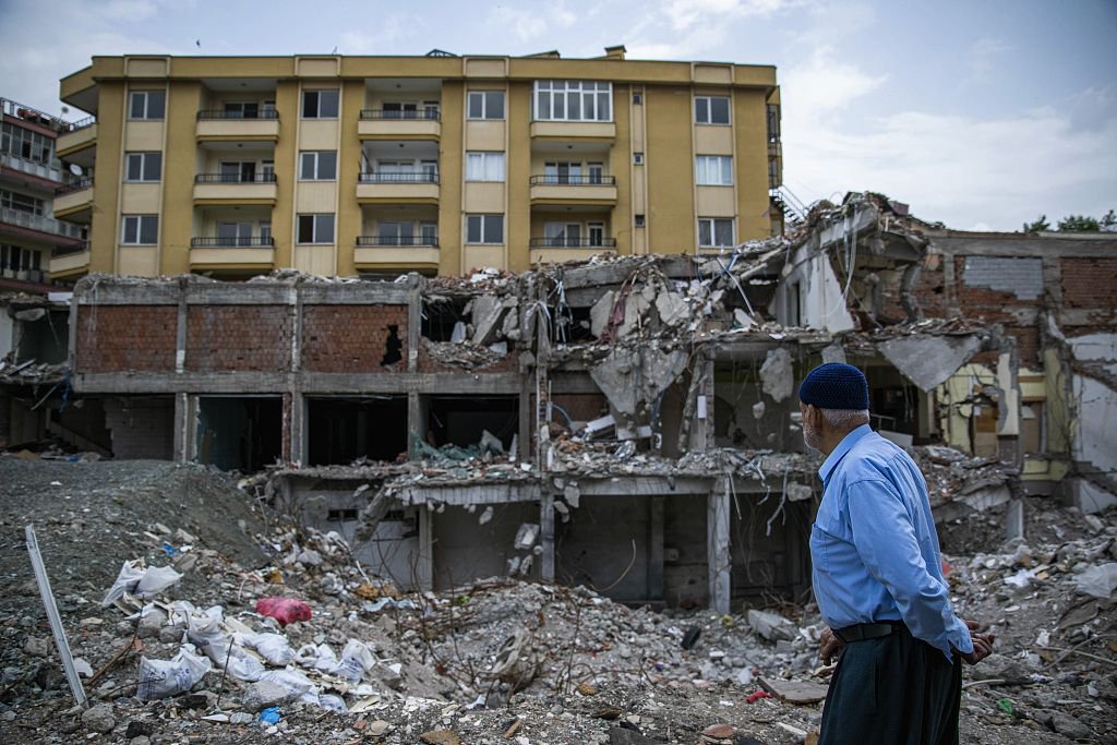 当地时间2023年5月23日，土耳其卡赫拉曼马拉什，一名男子走过因地震而受损的建筑物。