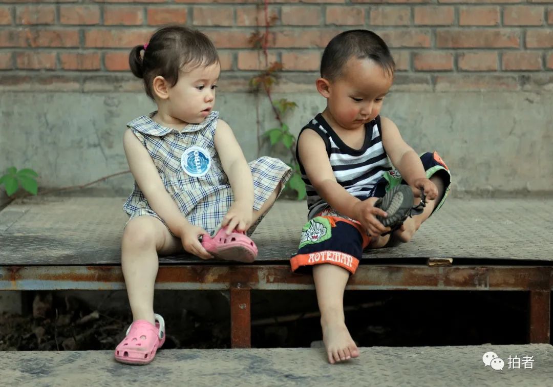 北京798艺术区,一个外国小女孩和一个中国小男孩学习穿鞋