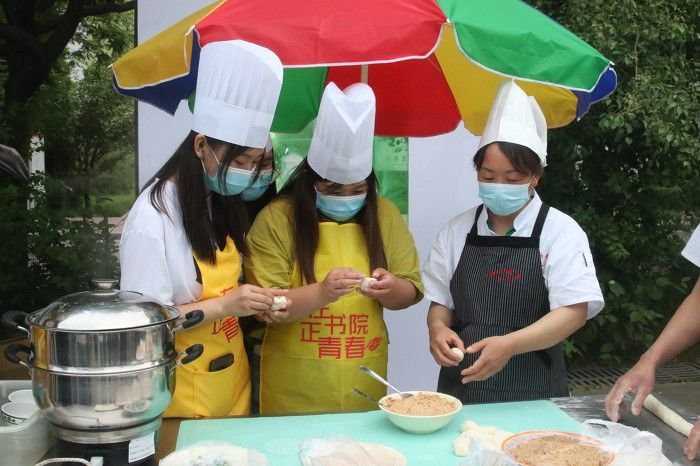 ▲学生们在食堂阿姨的指导下学习包饺子。