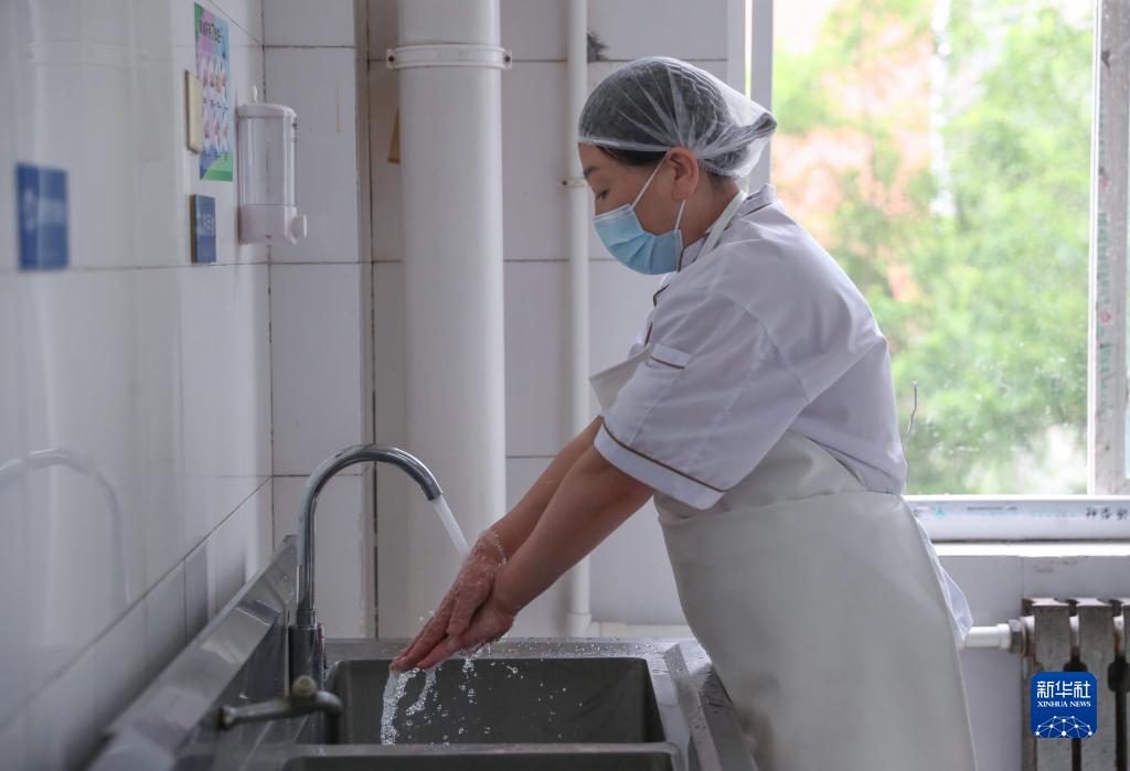 6月1日,沈阳市第一二0中学食堂工作人员在操作前洗手消毒.