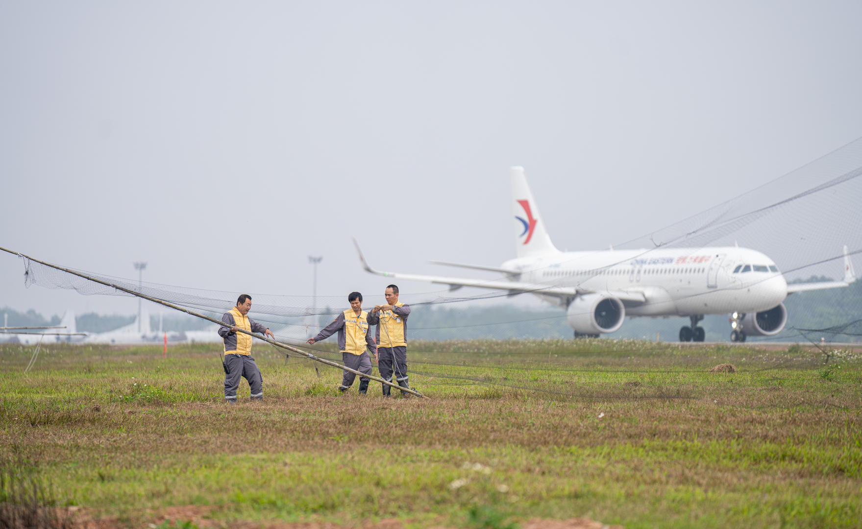 海南琼海博鳌机场停机坪上的驱鸟工作人员在机场旁重新布置捕鸟网.