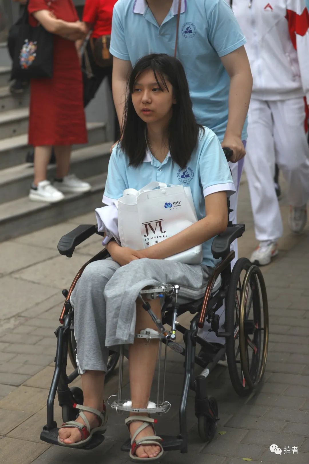 6月7日下午,人大附中考点,男同学推着左腿受伤的女同学进场考试.