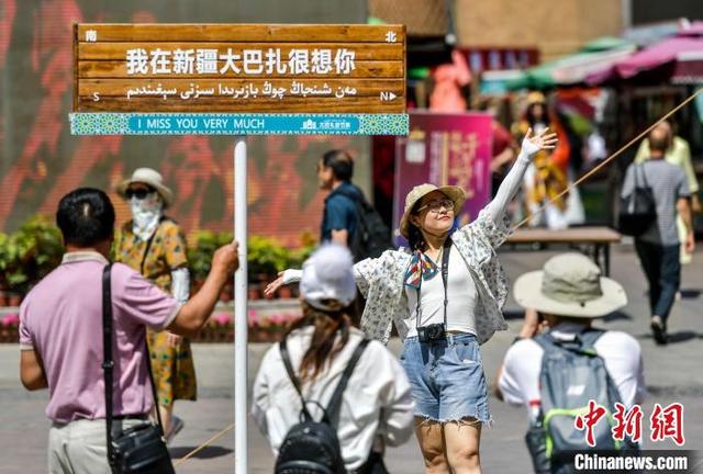 游客在个性路牌下拍照. 刘新 摄