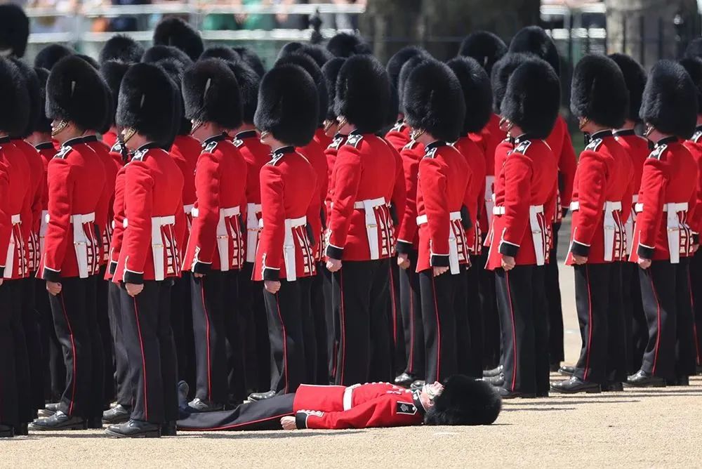 英国伦敦,在皇家卫队阅兵式上,一名卫兵在高温下晕倒