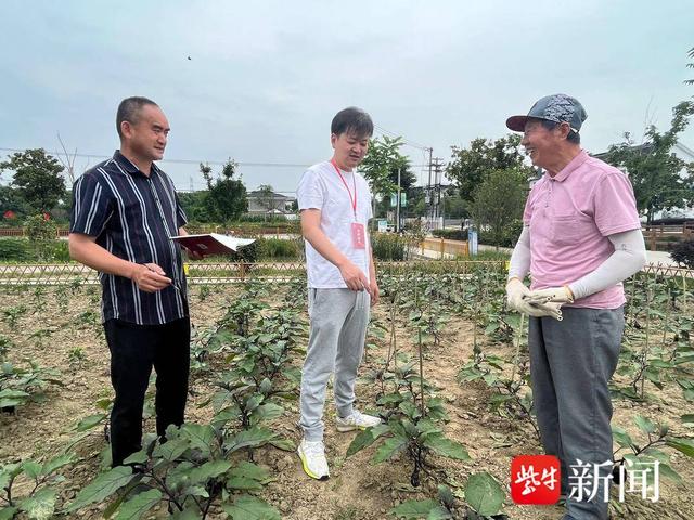 "双鹿村纪检委员钱峰正在详细询问菜地的种植管理人员,并记录相关情况