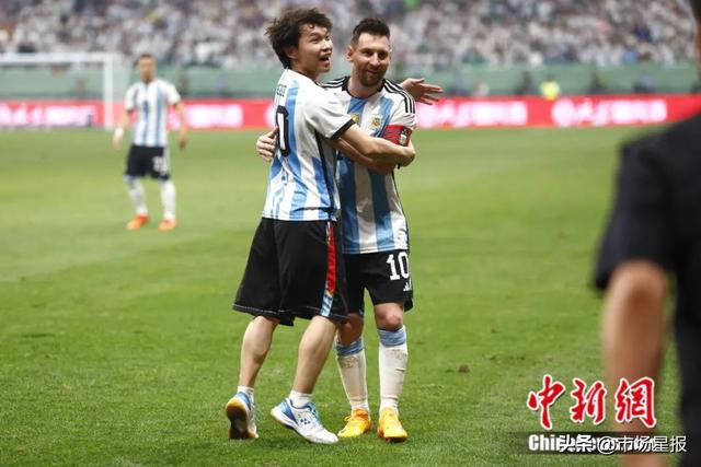 6月15日，在北京工人体育场举行的一场国际足球邀请赛中，一名球迷冲入赛场内拥抱阿根廷队球员梅西。中新社记者 富田 摄