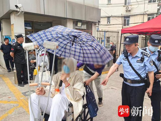 图为四所村派出所民警护送坐轮椅考生进考场