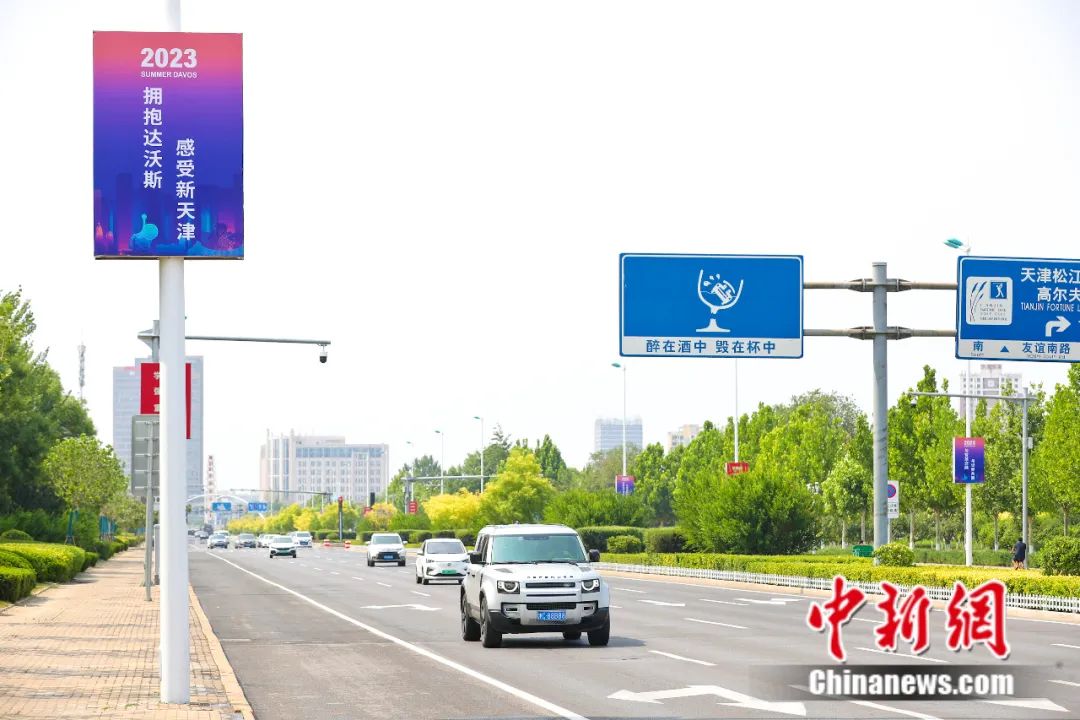 天津主干道,人行天桥悬挂着"拥抱达沃斯 感受新天津"等内容的宣传标语