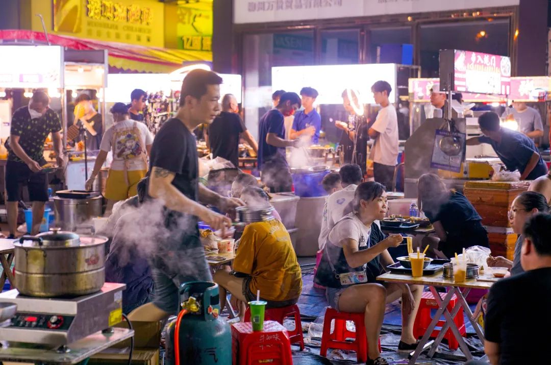 柳州北雀夜市的摊位上坐满了吃夜宵的人群.