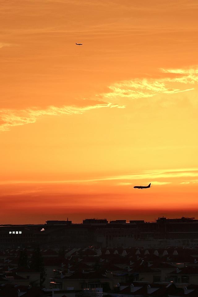 2023年7月9日,上海,绝美的晚霞铺满整片天空,两架飞机在空中交错,炎热