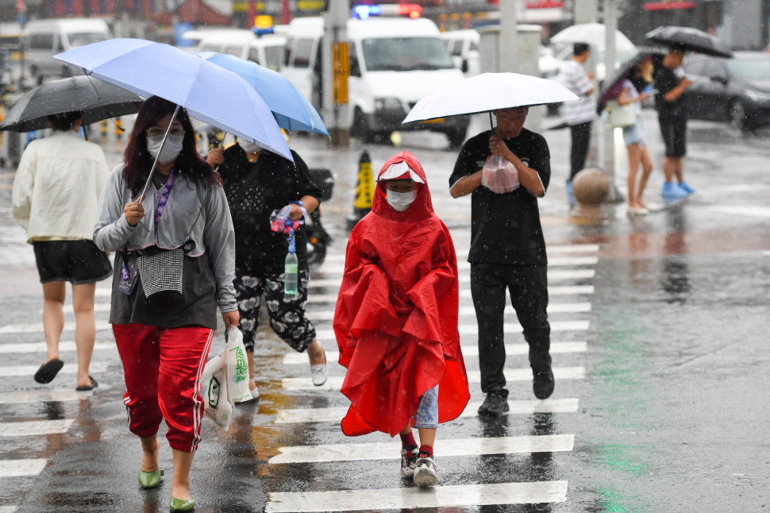 7月30日,在北京市朝阳区,行人冒雨行走在路上.新华社记者 鞠焕宗 摄