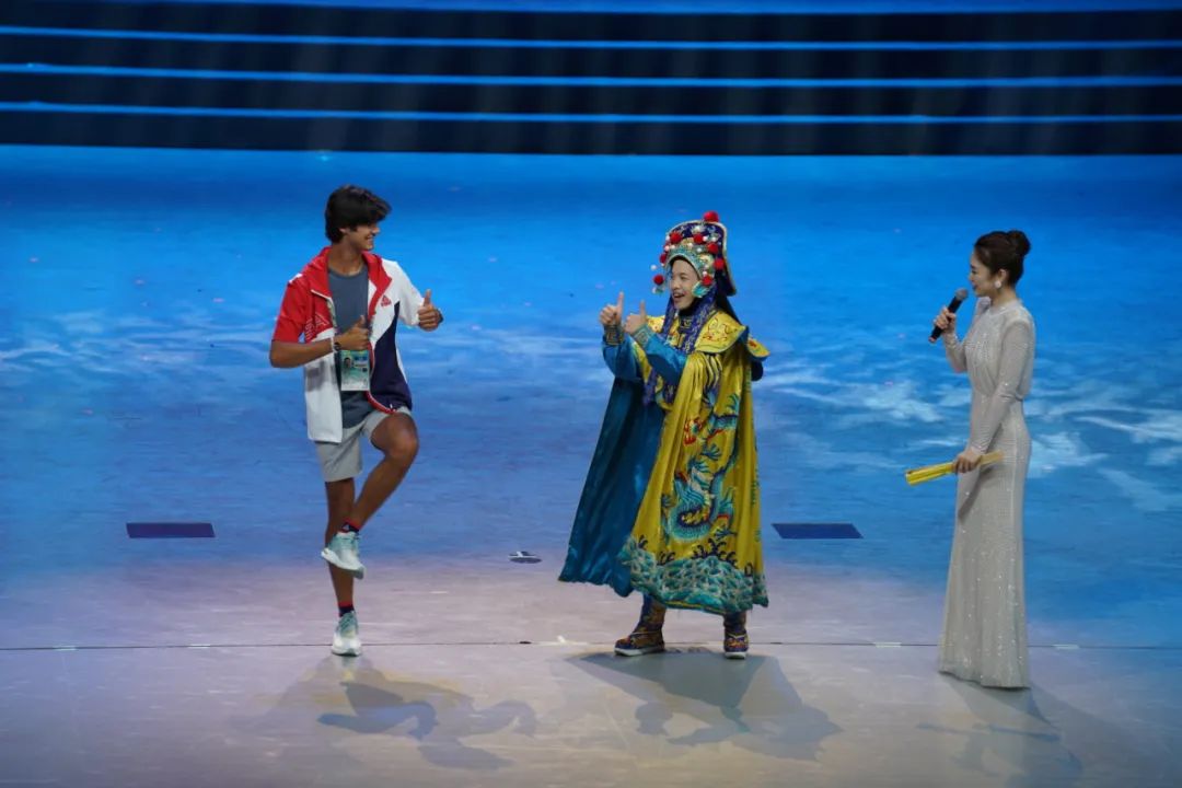 7月29日，美国运动员杜恩（左）在联欢会现场与川剧演员互动。朱晓帆摄