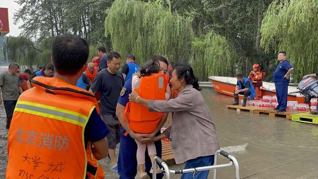 救援艇靠岸，救援人员将小女孩抱下船，交给家人手中。中青报·中青网记者 韩飏/摄