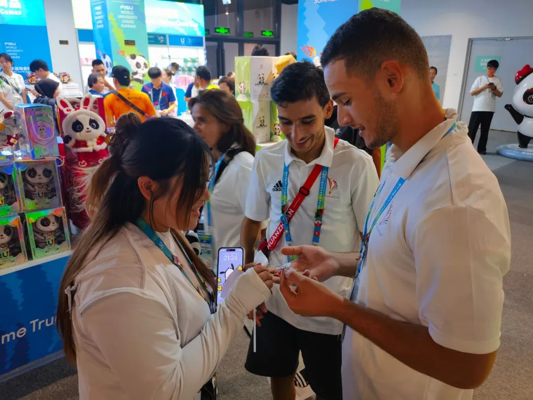 大运村特许商店里，外国运动员正在和志愿者交换徽章。朱晓帆摄