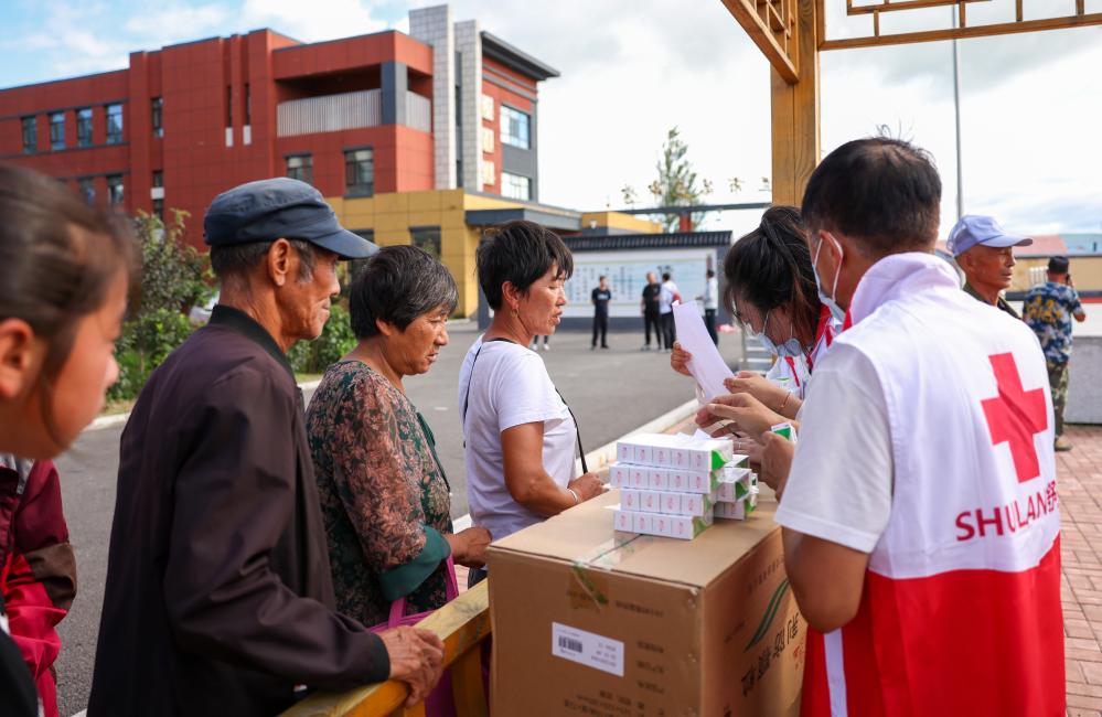 8月11日，村民在舒兰三中安置点领取舒兰市红十字会发放的药品物资。新华社记者颜麟蕴 摄