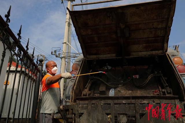 8月12日,北京市门头沟区丰沙铁路落坡岭车站旁,环卫工人正在对装垃圾